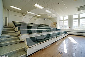 A large empty classroom with green seats and windows