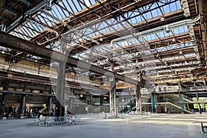 Large empty interior space of former heavy industry factory space. Large windows, beams, and rusted equipment, natural window