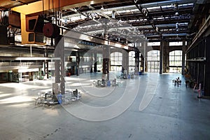 Large empty interior space of former heavy industry factory space. Large windows, beams, and rusted equipment, natural window