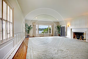 Large empty living room with fireplace and lake view.