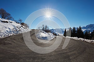 Large empty mountain road curve on Alps with snow on sides