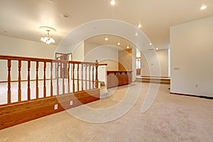 Large empty room with beige carpet and railing.