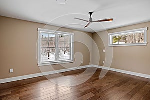 Large empty room with a ceiling fan and wood floors