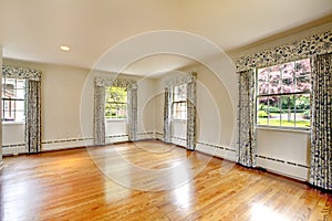 Large empty room with hardwood floor and curtains. Old luxury home.