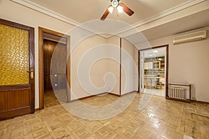 Large empty room with oak parquet floors and access doors