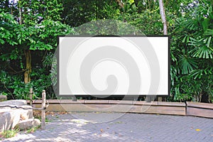 Large empty wooden signboard for advertising, map display or mockup comping purpose. Lush green background behind blank display photo