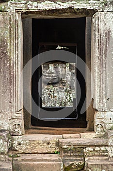 Large ethereal face carved in stone towers seen through stone doorway at the Bayon Temple, Angkor Wat, Cambodia