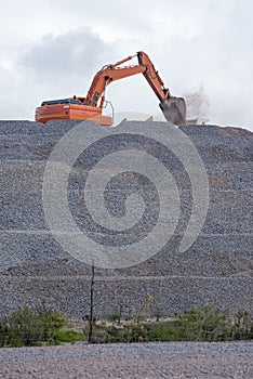 Large excavator on mountain of rocks