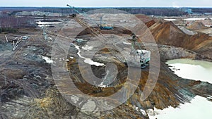 A large excavator works in the quarry. Drone view.