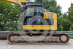 A large excavator in yellow color visible from the profile with a lowered bucket.