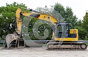 A large excavator in yellow color visible from the profile with a lowered bucket.