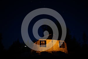 large expedition tent with protruding chimney from the furnace under the night starry sky