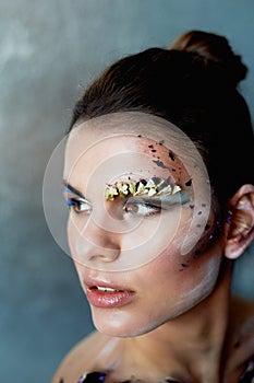Large-face portrait. Smears on her face. The make-up using dry colors.Creative personality, model.
