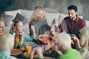 Large family gathering on thanksgiving day sit table enjoy october meal hold hands pray meeting mature relatives small