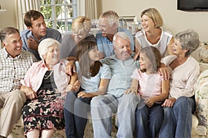 Large Family Group Sitting On Sofa Indoors