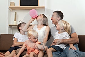 Large family at home preparing for the holiday. Mother inflating balloon, surprise dad