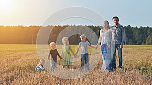 A large family is lined up and poses in front of the camera.