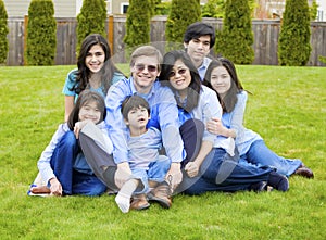 Large family of seven sitting together on lawn
