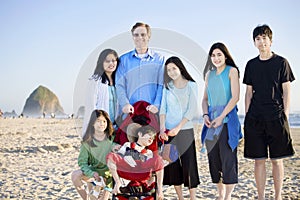 Large family of seven standing beach by ocean