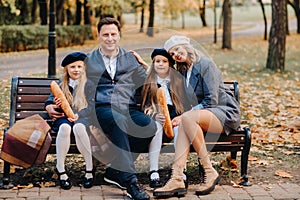 A large family is sitting on a bench in an autumn park. Happy people in the autumn park