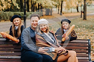 A large family is sitting on a bench in an autumn park. Happy people in the autumn park