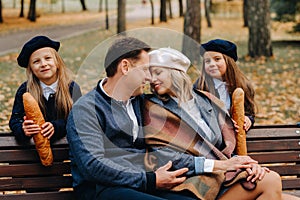 A large family is sitting on a bench in an autumn park. Happy people in the autumn park