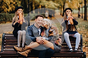 A large family is sitting on a bench in an autumn park. Happy people in the autumn park