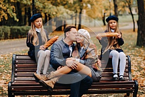 A large family is sitting on a bench in an autumn park. Happy people in the autumn park