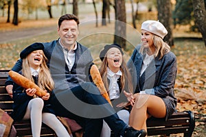 A large family is sitting on a bench in an autumn park. Happy people in the autumn park