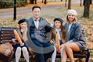 A large family is sitting on a bench in an autumn park. Happy people in the autumn park