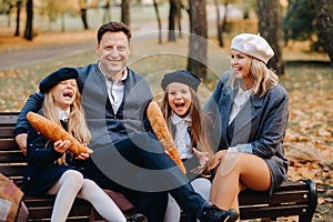 A large family is sitting on a bench in an autumn park. Happy people in the autumn park