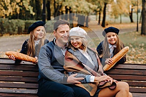 A large family is sitting on a bench in an autumn park. Happy people in the autumn park