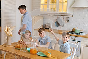 Large family with teenage children eating breakfast in kitchen. Caucasian