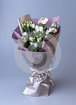 Large festive bouquet of white eustoma stands on a blue background.