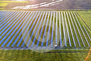 Large field of solar photo voltaic panels system producing renewable clean energy on green grass background