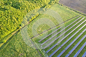 Large field of solar photo voltaic panels system producing renewable clean energy on green grass background