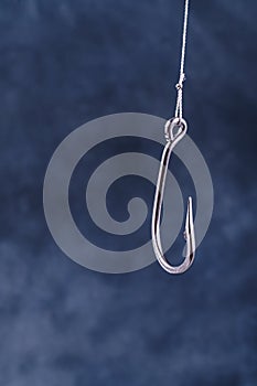 Large fishing hook on blue background with space for text