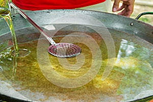 Large flat frying pan or skillet for paella or jambalaya on gas burner. Process of pouring and heating olive oil for cooking meat