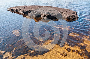 Large flat stone in lake in summer, Karelia, Russia