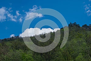 Large and fluffy cloud behind a hill covered with vegetation. Weather - concept