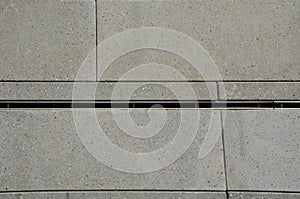 Large-format paving made of gray granite. the water is drained in the rain through a slotted stainless steel channel which is sunk