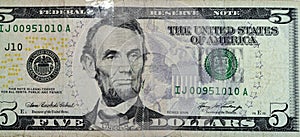 Large fragment of the obverse side of a torn 5 five dollars bill banknote repaired with adhesive plaster with the portrait of