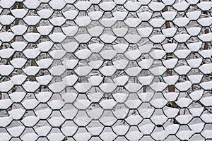 A large fragment of a snow-covered metal fence made of chain-link mesh