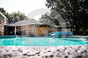 A large free form gray grey accent swimming pool with turquoise blue water in a fenced in backyard in a suburb