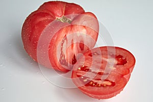 A large fresh cut tomato on an insulating white background