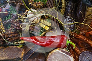 Large fresh red chili pepper on background of assortment of sausages
