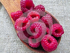 Large fresh red raspberry berries, poured into a wooden spoon