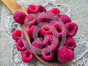 Large fresh red raspberry berries, poured into a wooden spoon