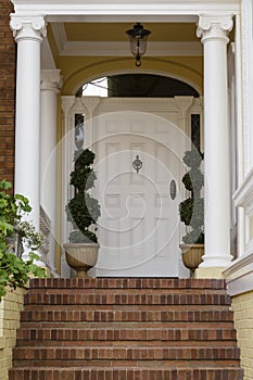 Large front door with white exterior with brick steps