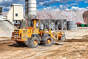 A large front loader transports materials in a concrete production plant. Production of concrete. Transportation of bulk materials